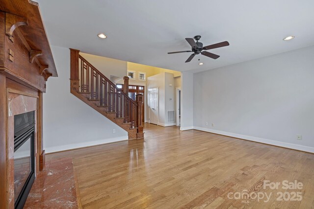 unfurnished living room featuring ceiling fan, a high end fireplace, and light hardwood / wood-style flooring