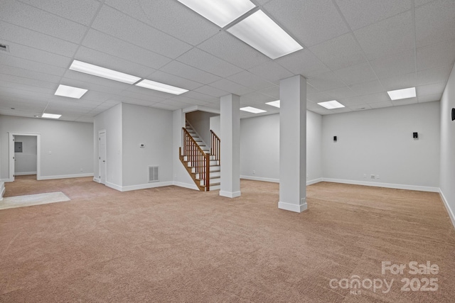 basement featuring a paneled ceiling and light carpet