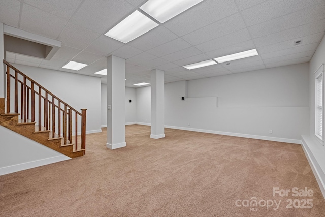 basement featuring a paneled ceiling and carpet