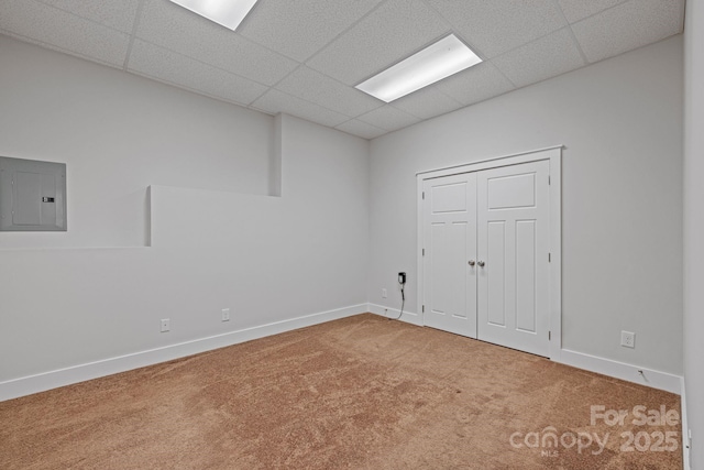 spare room with a drop ceiling, electric panel, and carpet