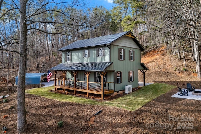 view of front of home featuring metal roof, a porch, a front lawn, and an outdoor fire pit