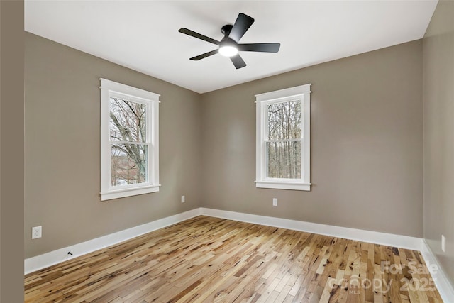 empty room featuring baseboards, a healthy amount of sunlight, a ceiling fan, and hardwood / wood-style flooring