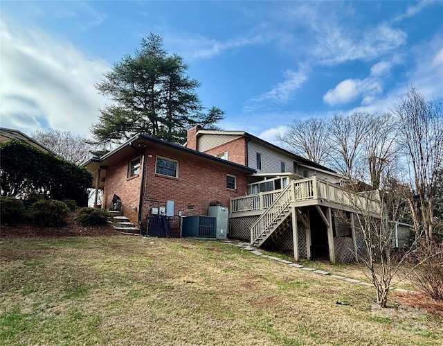 rear view of property featuring a wooden deck and a lawn