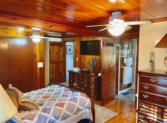 bedroom with a closet, light wood-type flooring, wood ceiling, and wood walls