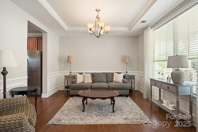 living room with a tray ceiling, dark wood-type flooring, and ornamental molding