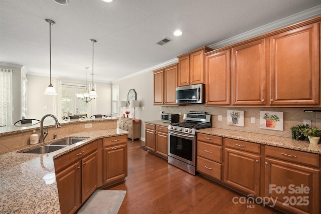 kitchen with appliances with stainless steel finishes, tasteful backsplash, sink, hanging light fixtures, and light stone counters