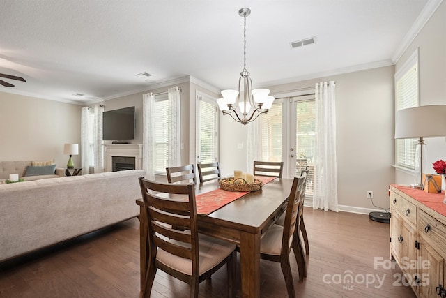 dining space with ceiling fan with notable chandelier, dark wood-type flooring, and ornamental molding