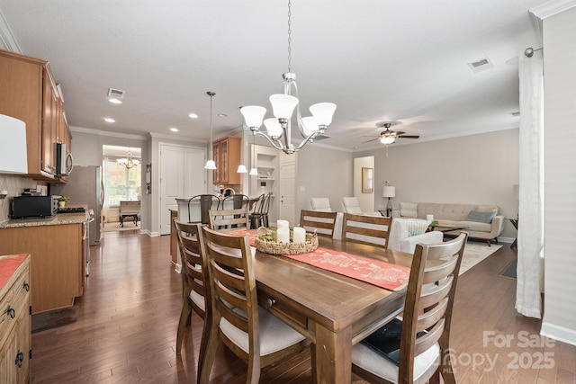 dining space featuring dark wood-type flooring, ornamental molding, and ceiling fan with notable chandelier