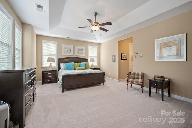 bedroom featuring a tray ceiling, light colored carpet, and ceiling fan