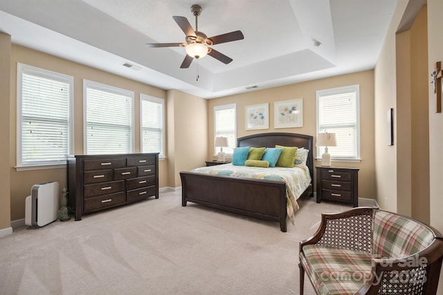 carpeted bedroom with a raised ceiling and ceiling fan