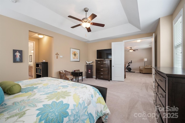 carpeted bedroom featuring ceiling fan and a raised ceiling