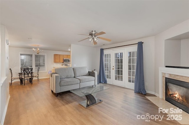 living room with a fireplace, light hardwood / wood-style flooring, and ceiling fan with notable chandelier