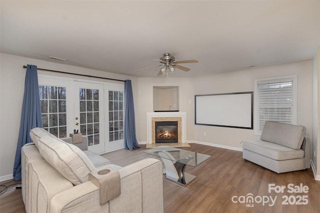 living room with a premium fireplace, ceiling fan, french doors, and wood-type flooring