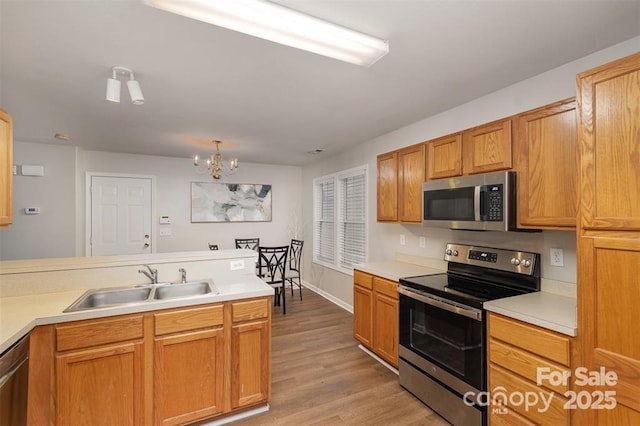 kitchen featuring an inviting chandelier, appliances with stainless steel finishes, sink, and light hardwood / wood-style flooring