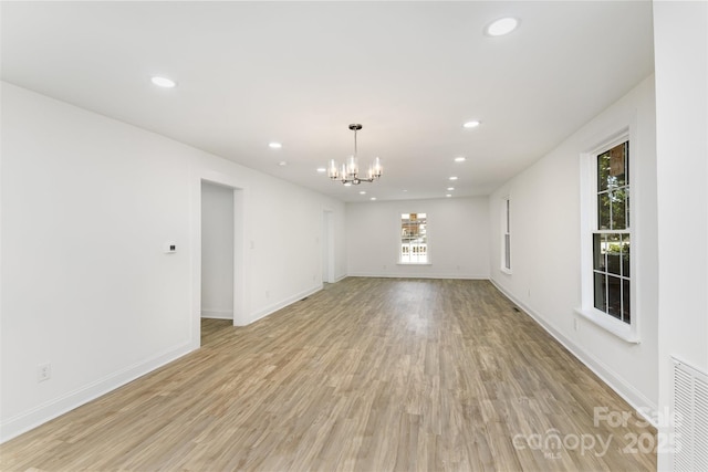 empty room with a notable chandelier and light wood-type flooring