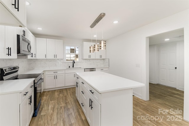 kitchen featuring pendant lighting, sink, stainless steel appliances, a center island, and white cabinets