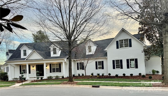 view of front of property featuring brick siding, a porch, and a front yard