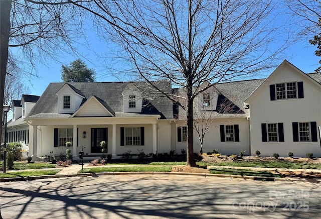 view of front of home with brick siding and roof with shingles