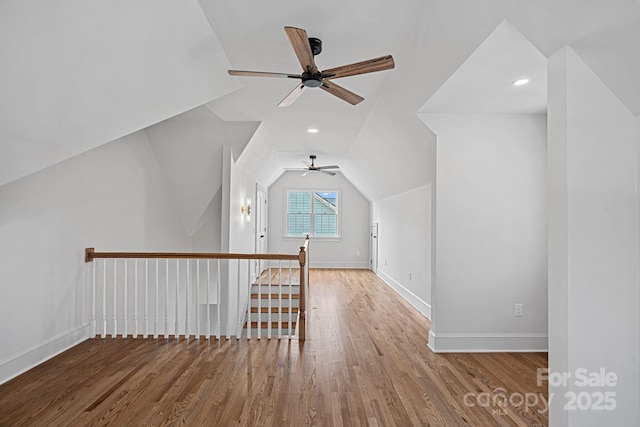 additional living space with baseboards, lofted ceiling, and wood finished floors