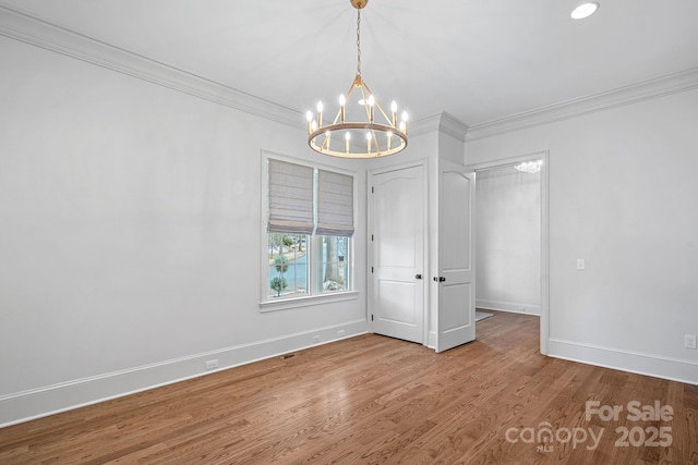 spare room with baseboards, a notable chandelier, wood finished floors, and ornamental molding