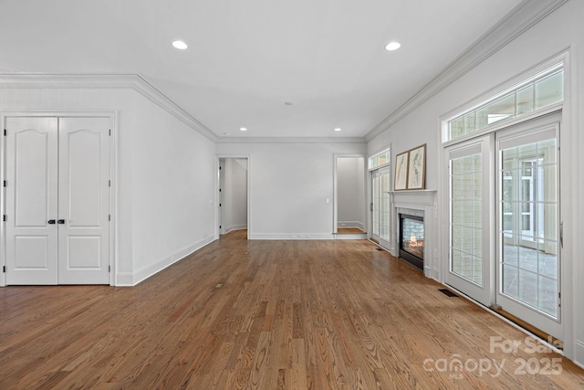 unfurnished living room with visible vents, a glass covered fireplace, wood finished floors, recessed lighting, and baseboards