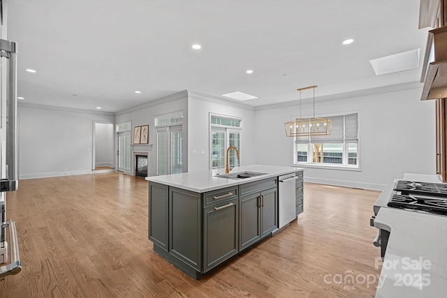 kitchen with light countertops, appliances with stainless steel finishes, a skylight, a fireplace, and a sink