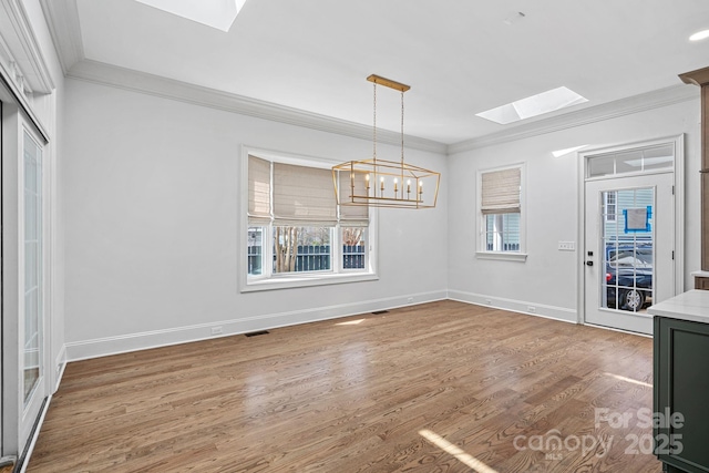 unfurnished dining area featuring wood finished floors, a skylight, visible vents, and ornamental molding