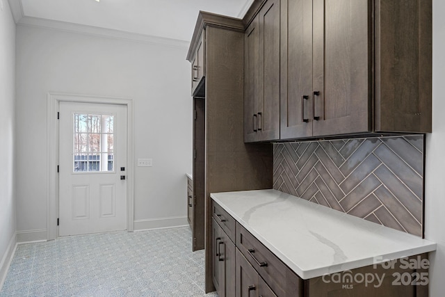 clothes washing area with crown molding and baseboards