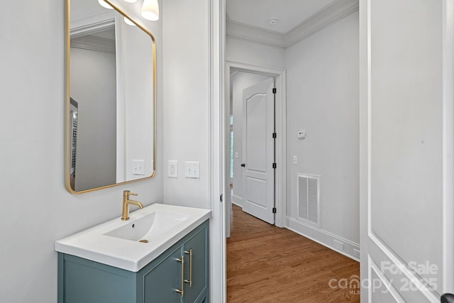 bathroom with vanity, crown molding, wood finished floors, and visible vents