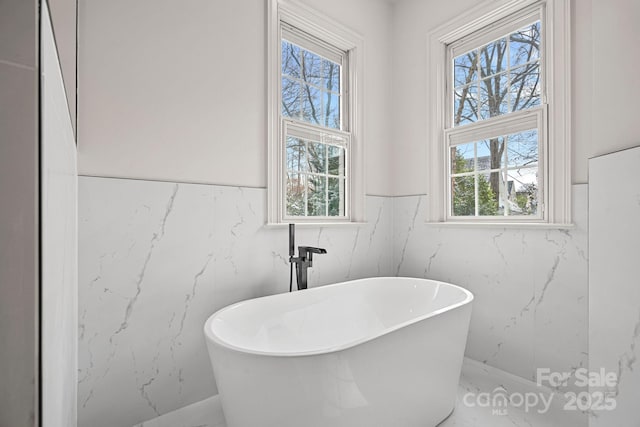 bathroom featuring a freestanding tub and a healthy amount of sunlight