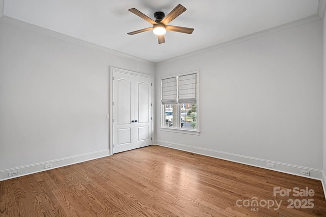 unfurnished room featuring ceiling fan, crown molding, baseboards, and wood finished floors