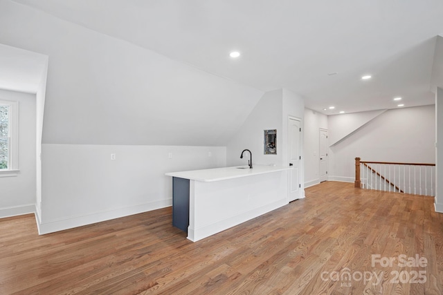 additional living space featuring lofted ceiling, light wood-type flooring, and baseboards