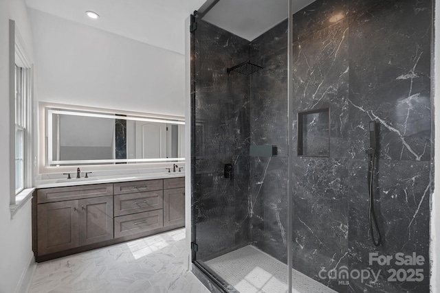 full bath featuring a sink, a marble finish shower, marble finish floor, and double vanity