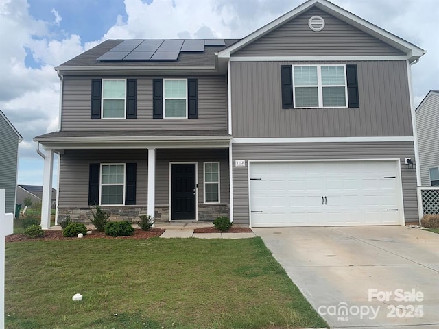 view of front facade featuring a garage, covered porch, a front lawn, and solar panels