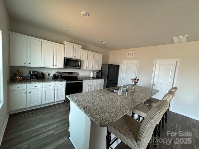 kitchen with white cabinetry, sink, electric range, and a kitchen island with sink