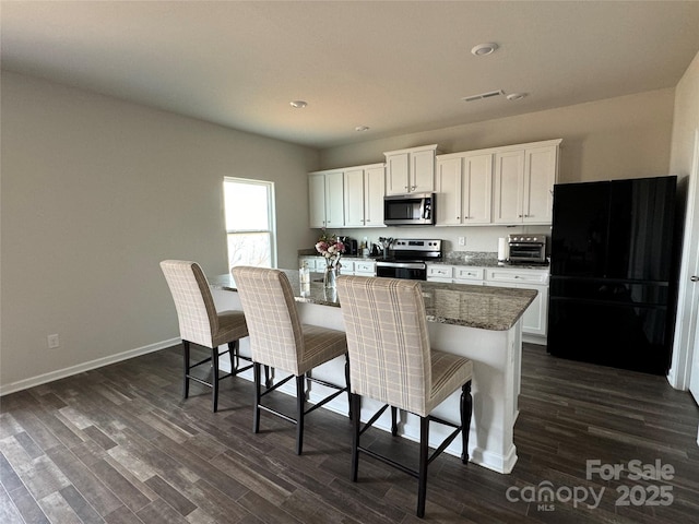 kitchen featuring stainless steel appliances, a kitchen breakfast bar, a kitchen island with sink, and white cabinets