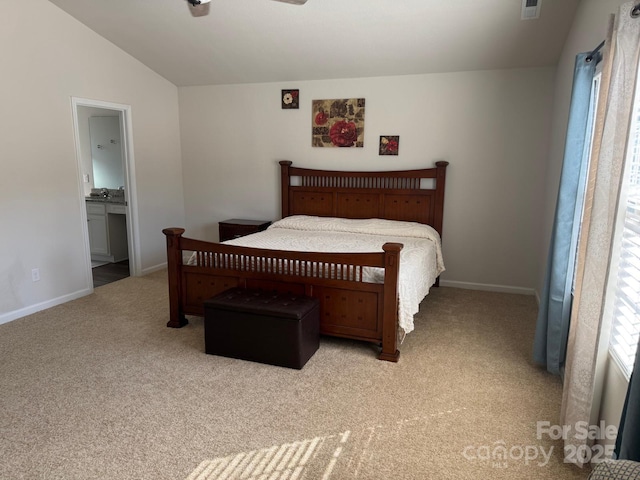 carpeted bedroom with ensuite bath and vaulted ceiling