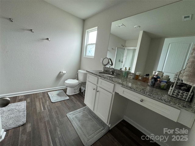 bathroom featuring vanity, toilet, a shower with shower door, and hardwood / wood-style floors