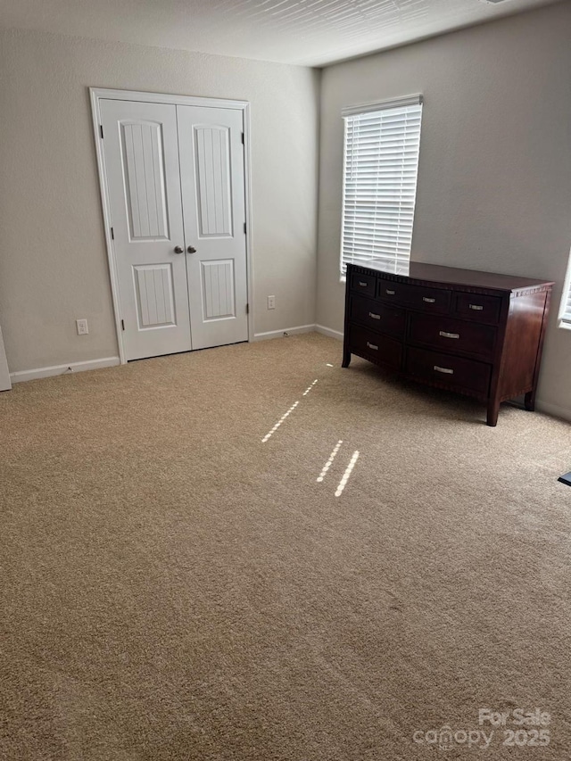 unfurnished bedroom with light colored carpet and a closet