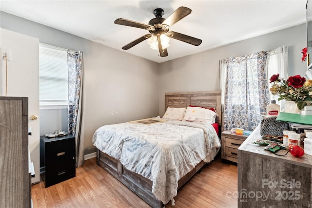 bedroom featuring ceiling fan, multiple windows, and light hardwood / wood-style flooring