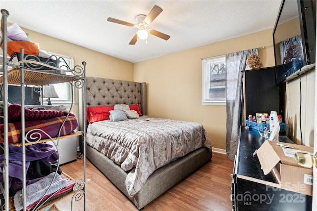 bedroom with ceiling fan, hardwood / wood-style floors, and a textured ceiling