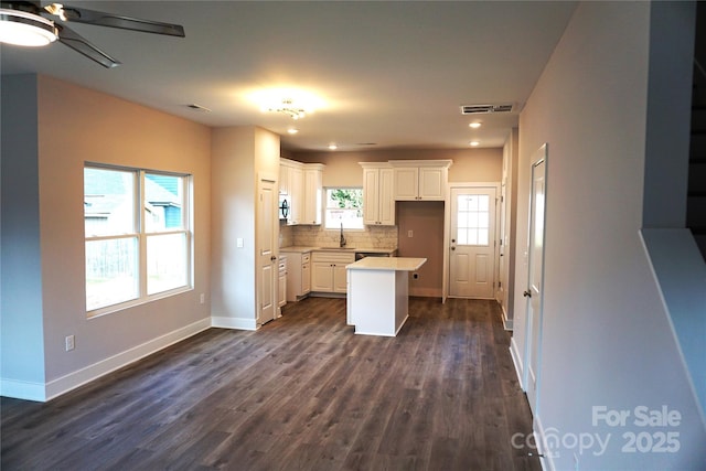 kitchen with tasteful backsplash, a kitchen island, dark hardwood / wood-style floors, and white cabinets