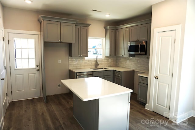 kitchen with dark wood-type flooring, sink, tasteful backsplash, a center island, and stainless steel appliances