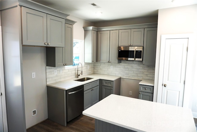 kitchen with sink, appliances with stainless steel finishes, gray cabinetry, tasteful backsplash, and dark hardwood / wood-style flooring