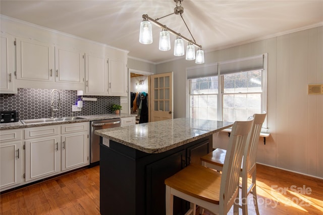 kitchen featuring sink, a center island, hanging light fixtures, dishwasher, and light stone countertops