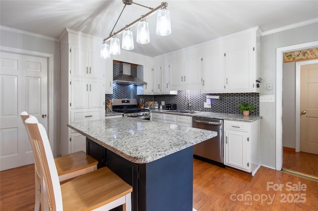 kitchen with white cabinets, decorative light fixtures, stainless steel appliances, and wall chimney exhaust hood