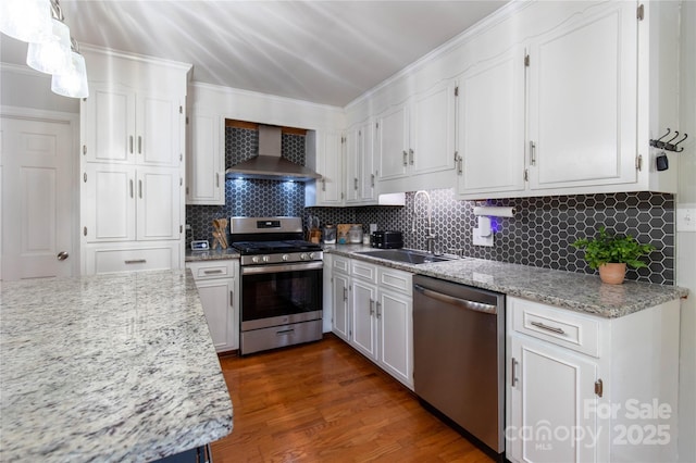 kitchen with sink, white cabinets, backsplash, stainless steel appliances, and wall chimney range hood