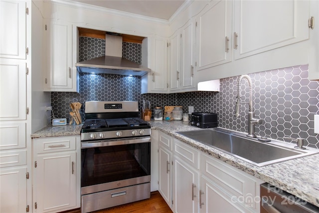 kitchen featuring appliances with stainless steel finishes, sink, wall chimney range hood, and white cabinets