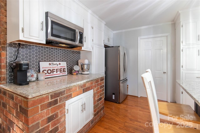 kitchen with white cabinetry, crown molding, light hardwood / wood-style flooring, and stainless steel appliances