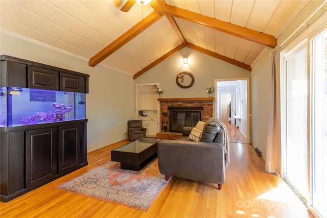 living room featuring vaulted ceiling with beams, a fireplace, light hardwood / wood-style floors, and ceiling fan